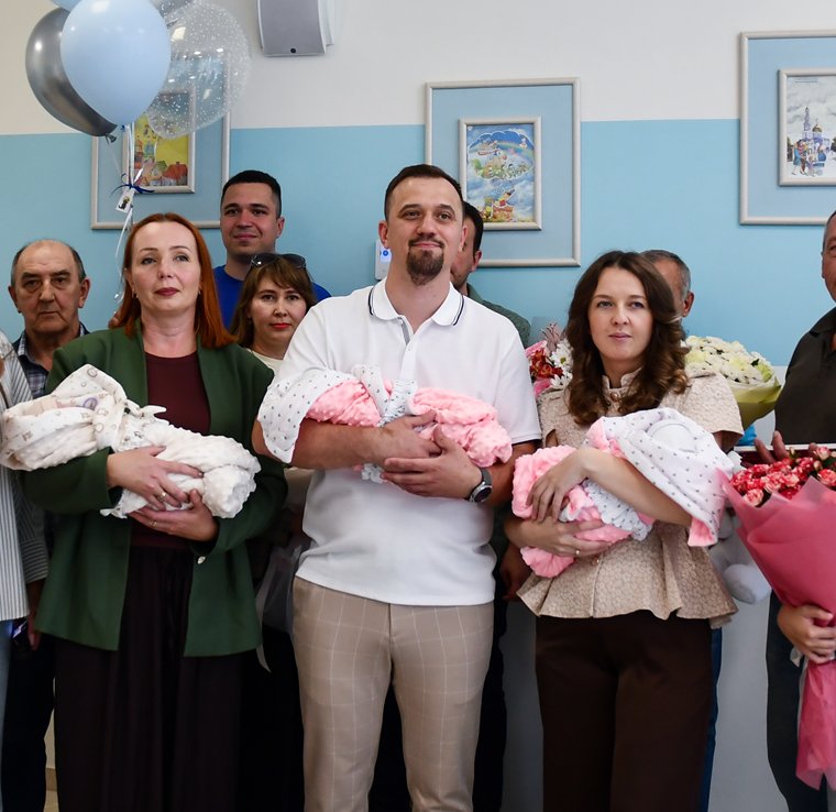 Родители держат на руках новорождённую тройню